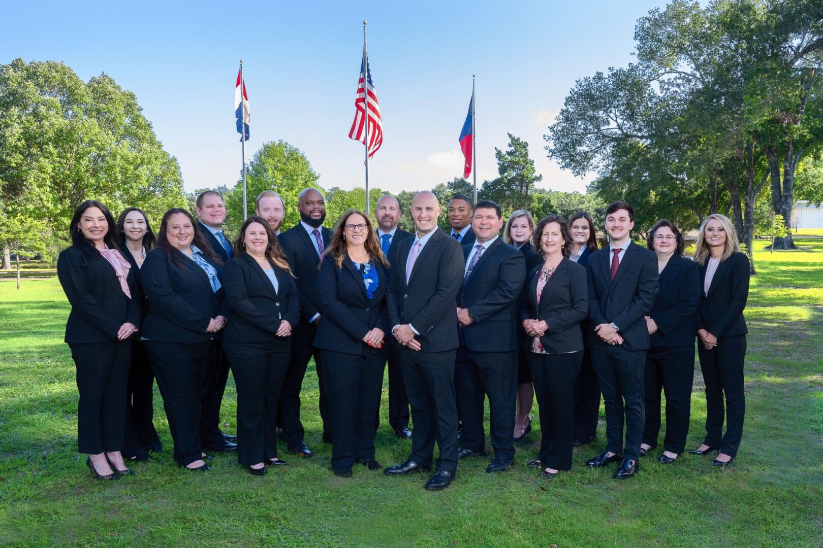 A group of people in suits and ties standing on top of grass.