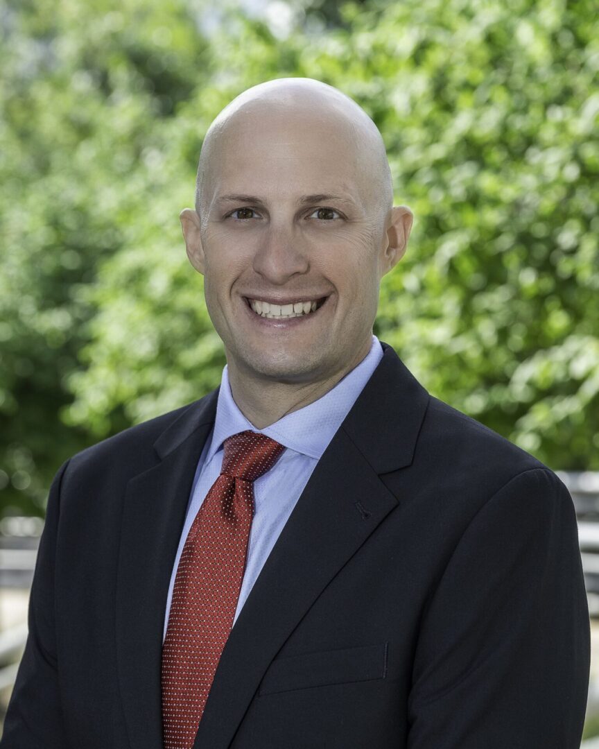 A man in suit and tie smiling for the camera.